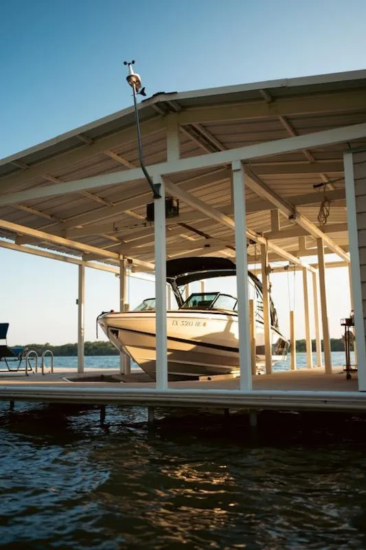 Slide: The Image of 2016 Regal 2100 Bowrider docked under a covered boathouse on a sunny day. - 18