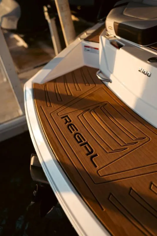Slide: The Image of 2016 Regal 2100 Bowrider boat deck with logo, featuring sleek design and wood finish. - 20