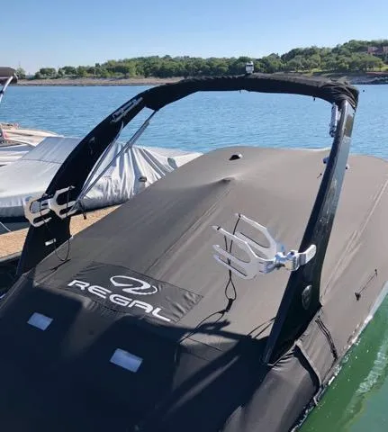 Slide: The Image of 2016 Regal 2100 Bowrider boat with cover on a sunny day by the water. - 24