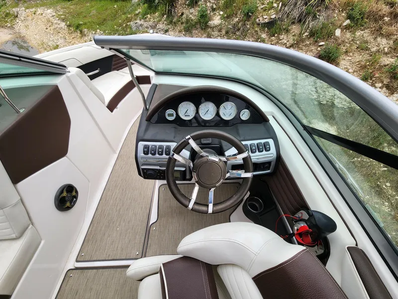 Slide: The Image of 2016 Regal 2100 Bowrider boat cockpit with steering wheel and dashboard controls. - 6