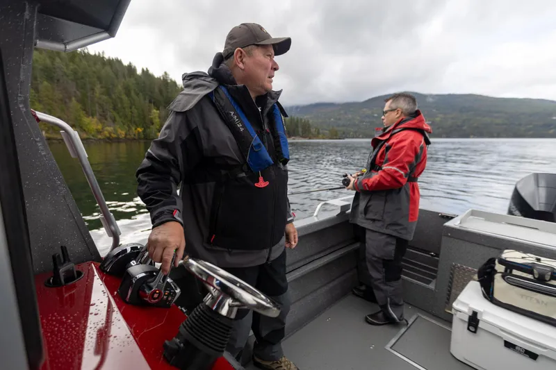 Slide: The Image of Two people on a 2024 Spartan 240 Maximus Pro boat in a scenic lake setting. - 16