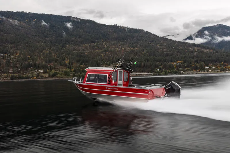 Slide: The Image of 2024 Spartan 240 Maximus Pro boat speeding on a lake with mountainous backdrop. - 8