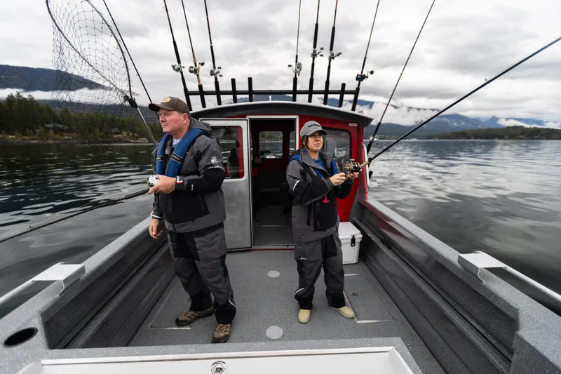 Slide: The Image of Two people fishing on a 2024 Spartan 240 Maximus Pro boat in a scenic lake. - 9
