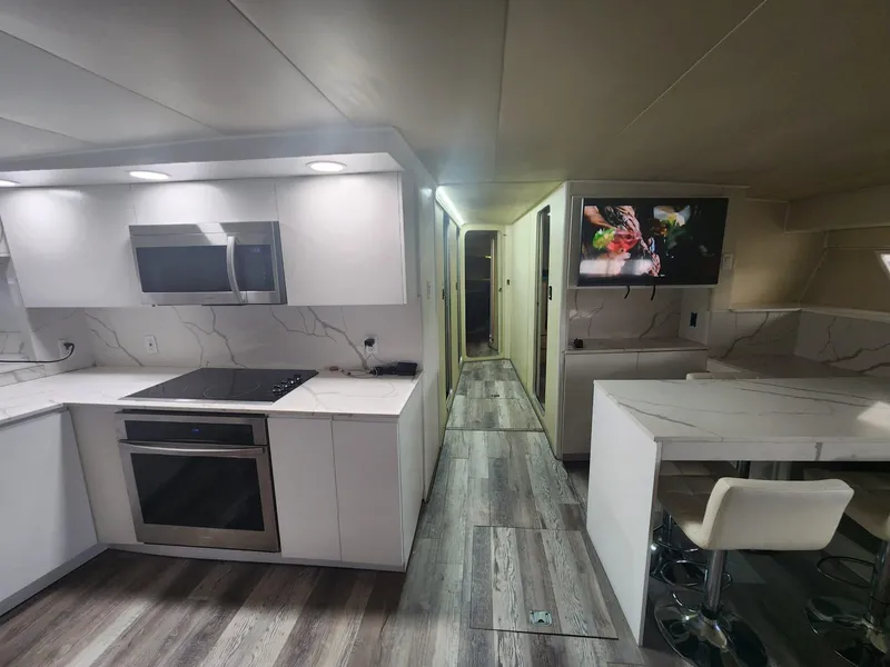 Slide: The Image of Modern kitchen and dining area in 1984 Infinity Express RV with sleek white cabinetry. - 14