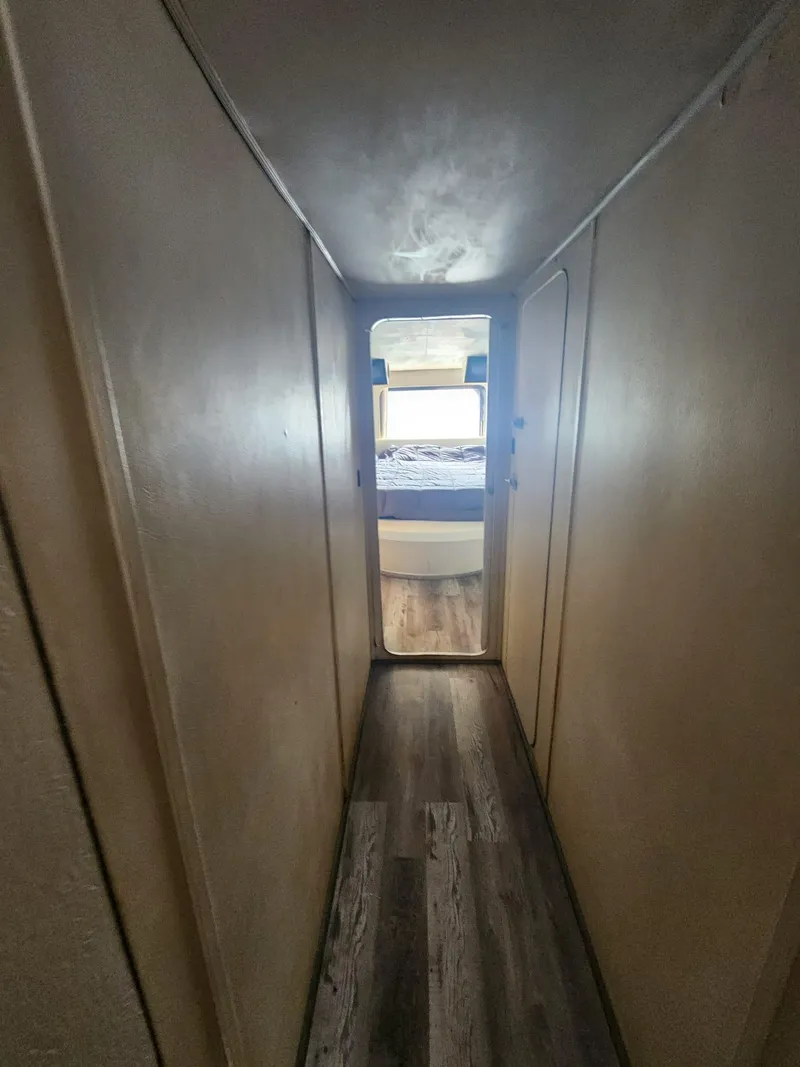 Slide: The Image of Narrow hallway in 1984 Infinity Express RV leading to a bedroom with wood flooring. - 23