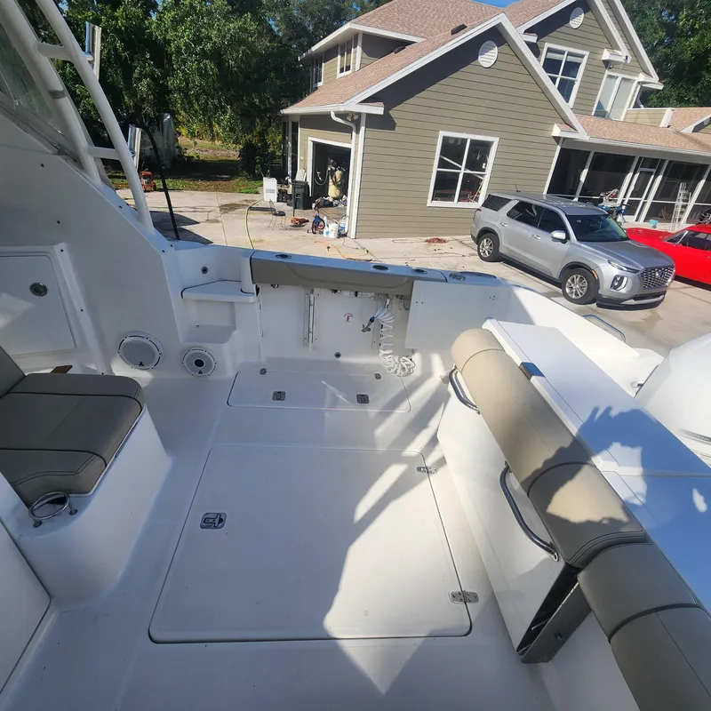 Slide: The Image of 2020 Pursuit OS 325 Offshore boat interior with seating, parked near a house and cars. - 18