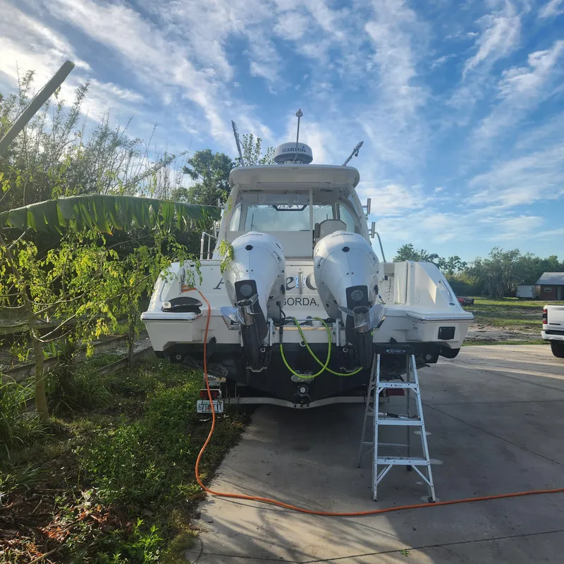 Slide: The Image of 2020 Pursuit OS 325 Offshore boat with dual outboard motors on a driveway. - 2