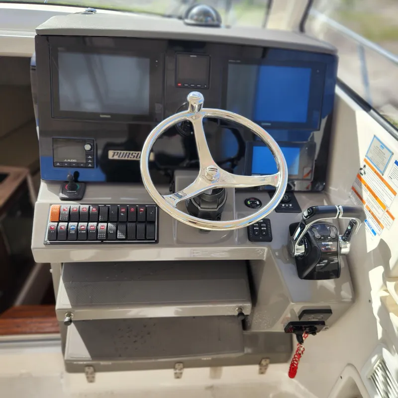 Slide: The Image of Helm station of a 2020 Pursuit OS 325 Offshore boat with steering wheel and control panel. - 23