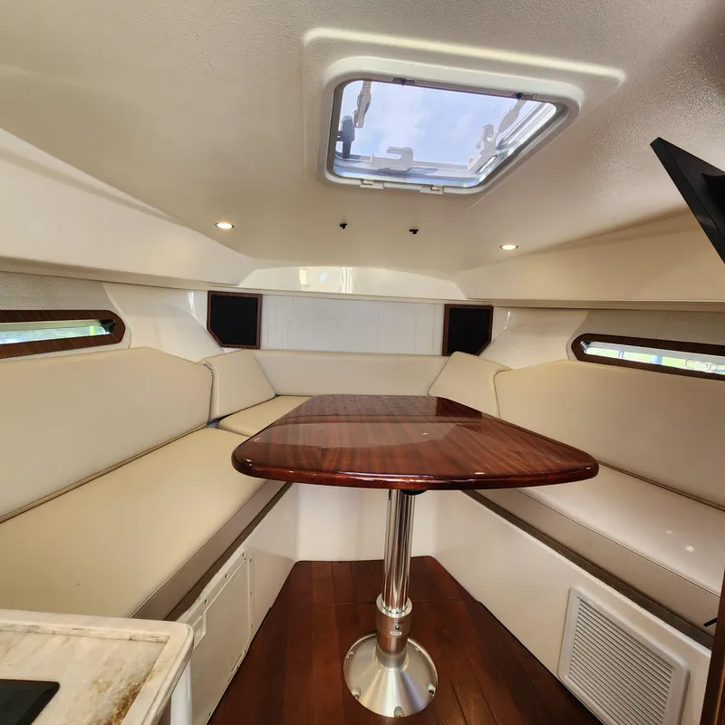 Slide: The Image of Interior cabin of 2020 Pursuit OS 325 Offshore boat with wooden table and beige seating. - 29