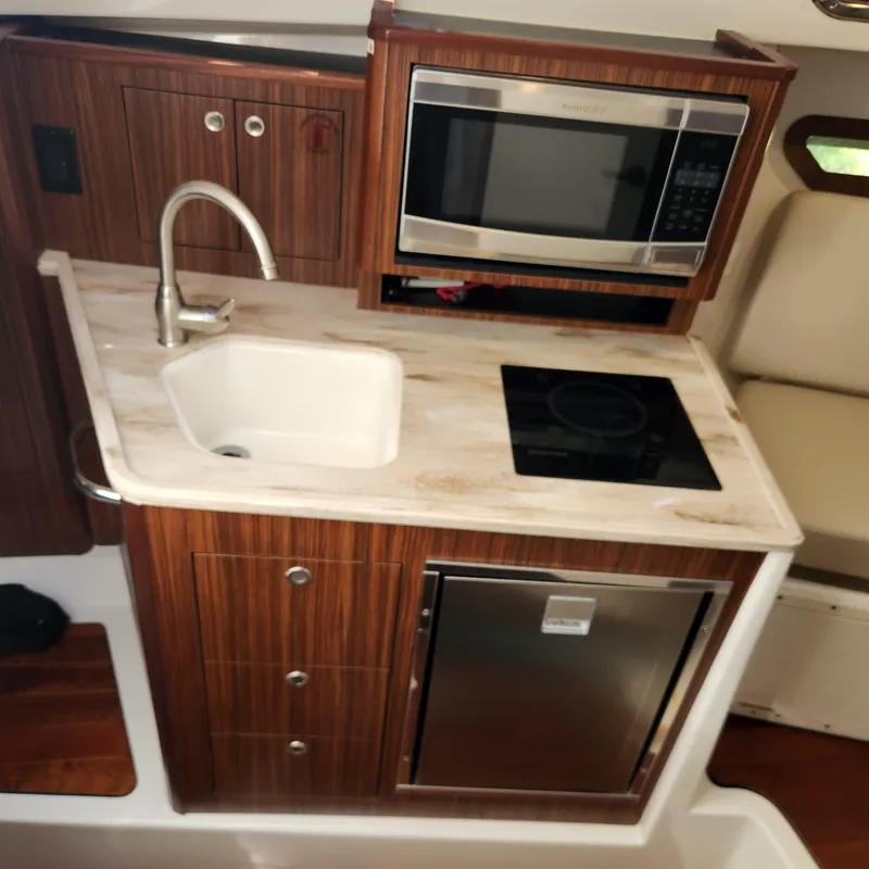 Slide: The Image of Compact kitchen area in 2020 Pursuit OS 325 Offshore boat with sink, microwave, and stove. - 32