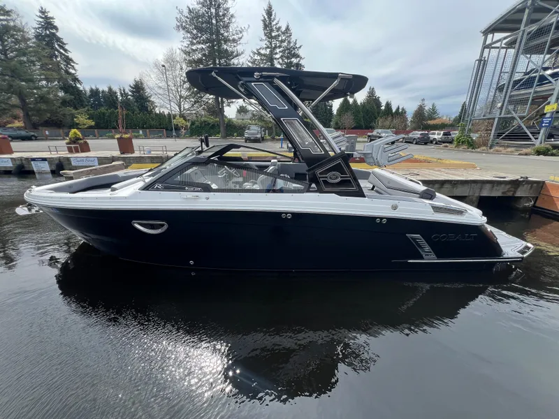Slide: The Image of 2024 Cobalt R6 Surf boat docked on calm water, showcasing sleek design and modern features. - 1