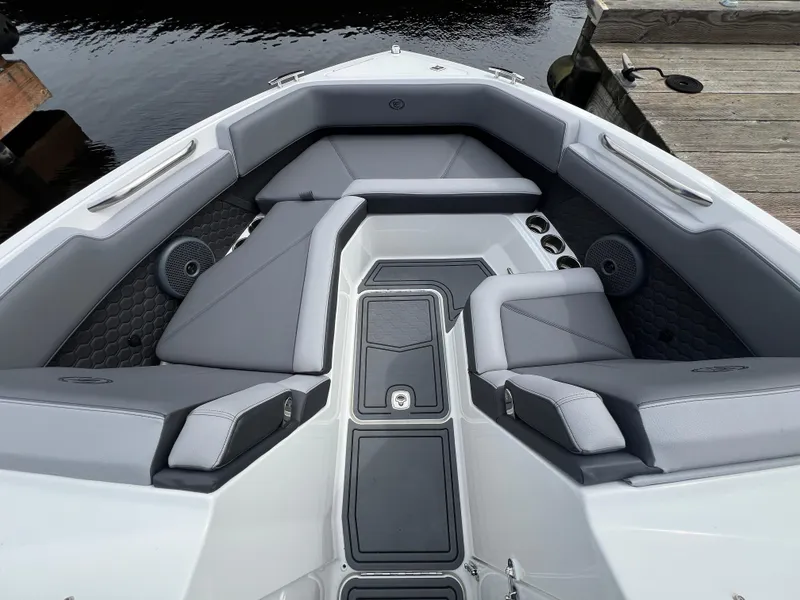 Slide: The Image of 2024 Cobalt R6 Surf boat interior with gray seating and cup holders, docked by water. - 20