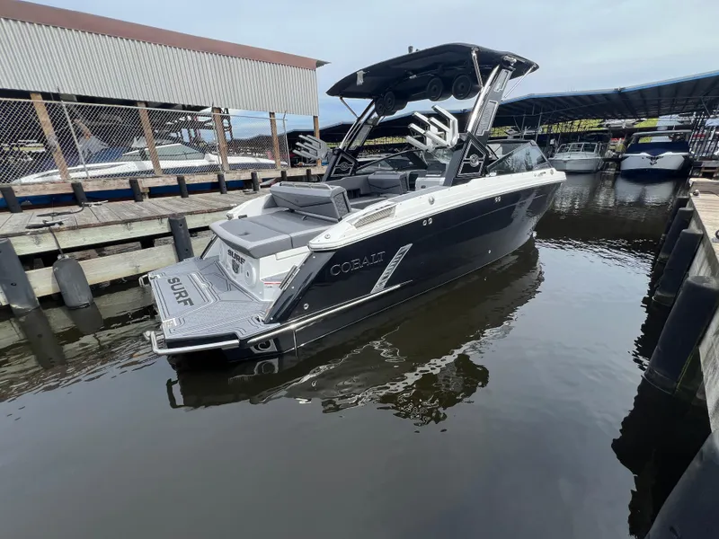 Slide: The Image of 2024 Cobalt R6 Surf boat docked in marina, sleek black design. - 5