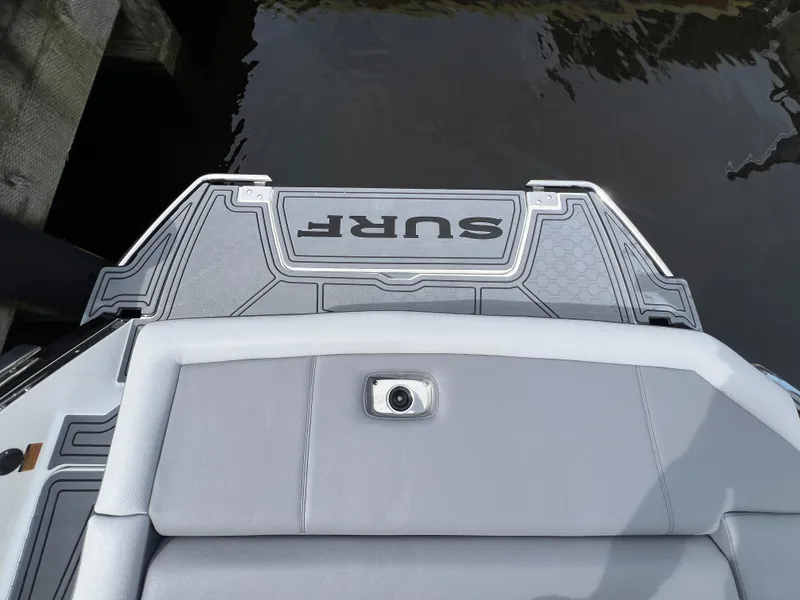Slide: The Image of 2024 Cobalt R6 Surf boat's rear deck with "SURF" branding, docked by water. - 8