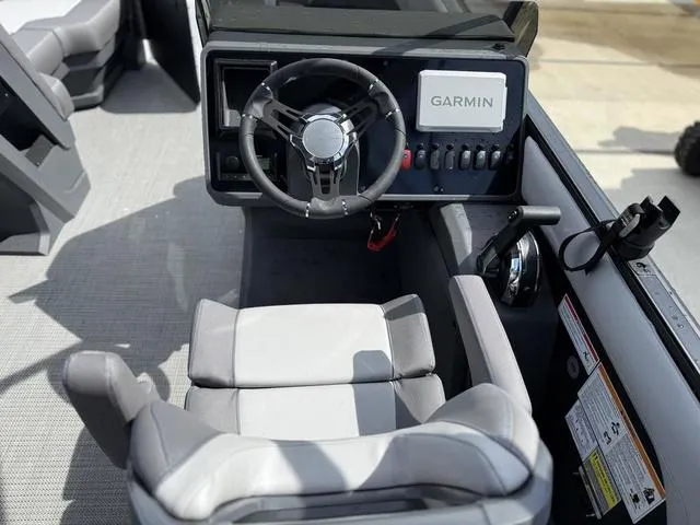 Slide: The Image of 2024 Manitou Cruise 22 Max Switchback V-Toon interior with tractor and trailer in background. - 8