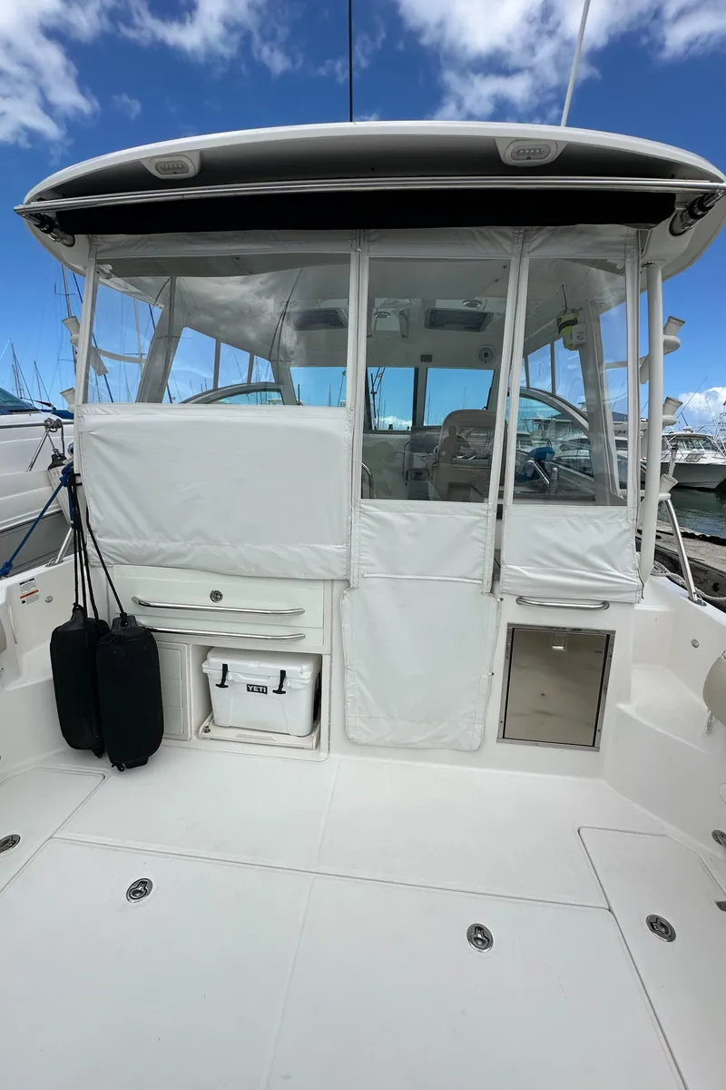 Slide: The Image of 2015 Boston Whaler 345 Conquest boat with enclosed cockpit, docked under blue sky. - 2