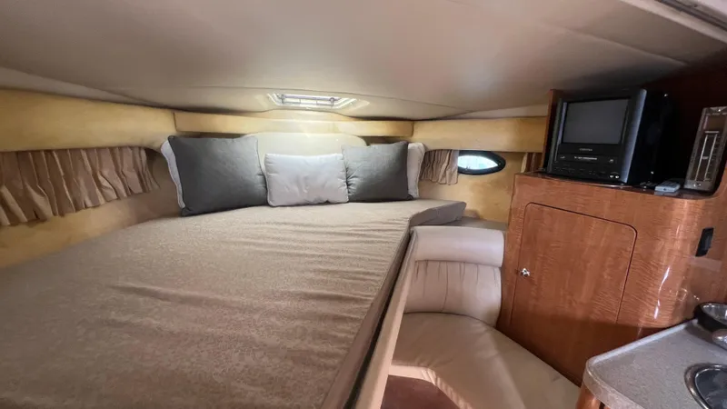 Slide: The Image of 2003 Regal Commodore 3260 cabin interior with bed, TV, and wooden cabinetry. - 42
