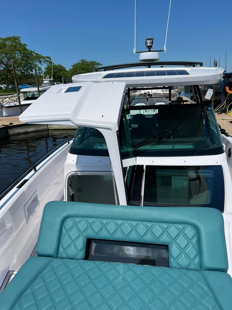 Slide: The Image of 2022 Axopar 37 Sun Top boat docked, featuring teal seating and open cabin door. - 27