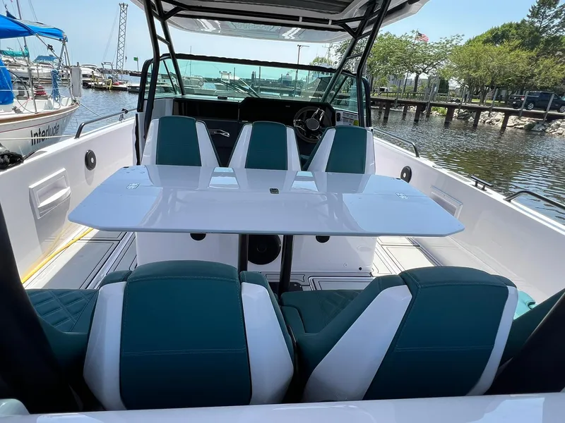 Slide: The Image of 2022 Axopar 37 Sun Top boat interior with seating and table, docked at marina. - 33