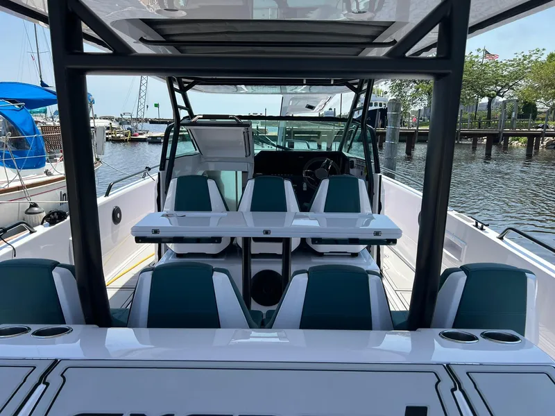 Slide: The Image of 2022 Axopar 37 Sun Top boat interior with seating and table, docked at marina. - 8