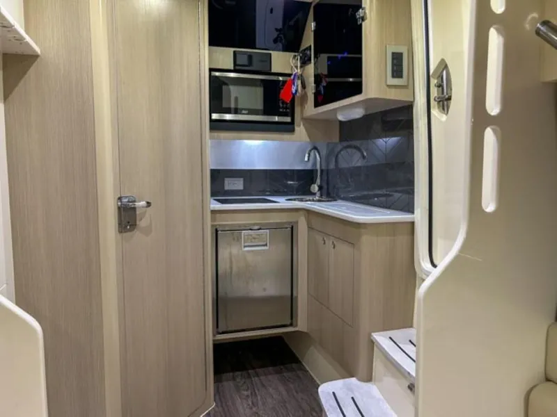 Slide: The Image of 2023 Scout 400 LXF boat interior kitchen with modern appliances and wooden cabinetry. - 16
