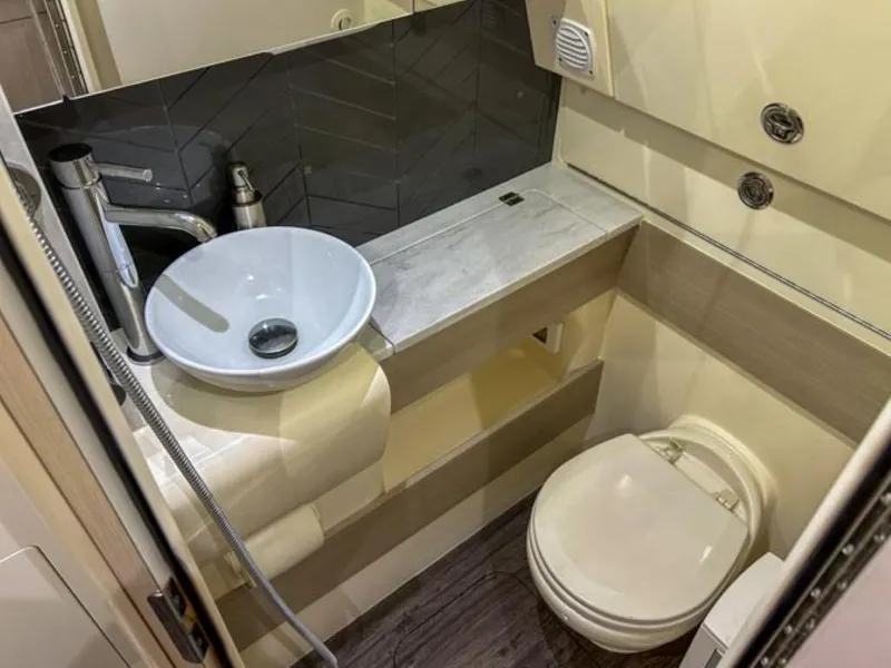 Slide: The Image of 2023 Scout 400 LXF boat bathroom with modern sink, toilet, and storage. - 19