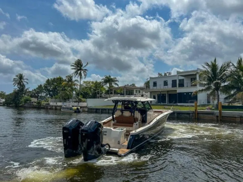 Slide: The Image of 2023 Scout 400 LXF boat cruising near waterfront homes under a partly cloudy sky. - 5