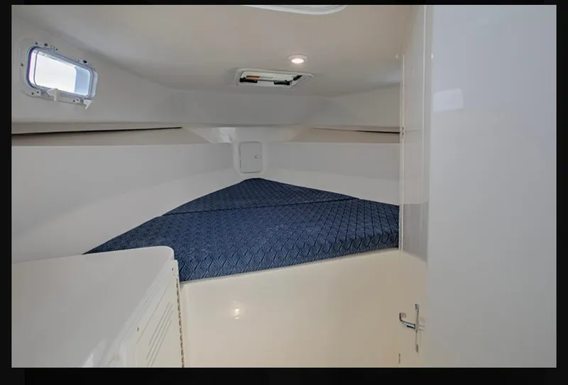 Slide: The Image of Interior cabin of 2024 NorthCoast 255 Cabin boat with blue bedding. - 25