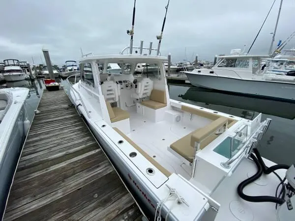 Slide: The Image of 2024 NorthCoast 255 Cabin boat docked at marina, featuring spacious seating and fishing rods. - 34