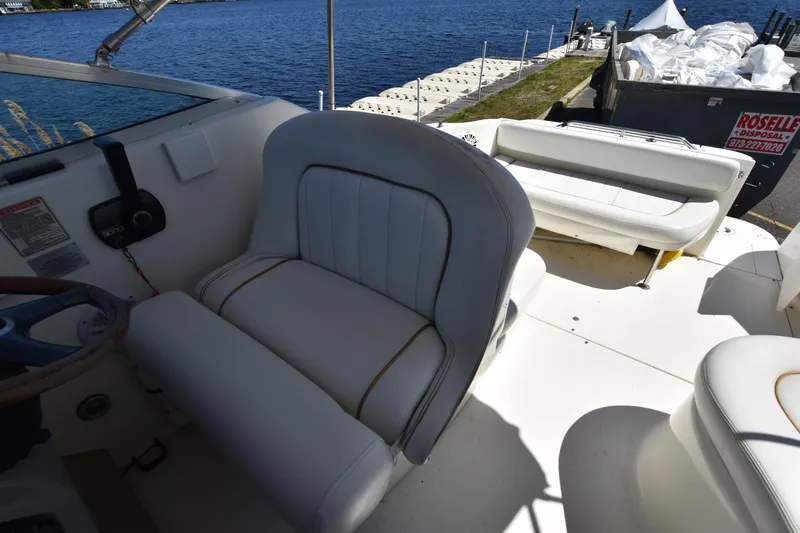 Slide: The Image of 1998 Sea Ray 270 Sundancer boat interior with white seating, docked by the water. - 10