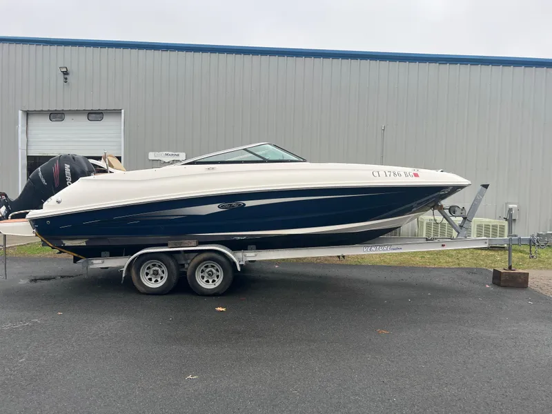 The Image of 2014 Sea Ray 240 Sundeck Outboard on a trailer outside a warehouse. - 0