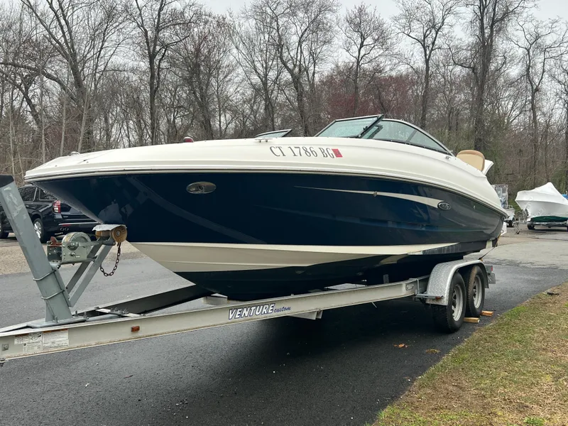 Slide: The Image of 2014 Sea Ray 240 Sundeck Outboard on trailer in wooded area. - 2