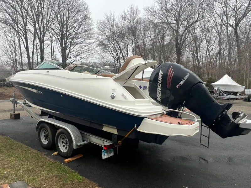 Slide: The Image of 2014 Sea Ray 240 Sundeck Outboard boat on a trailer in a wooded area. - 3