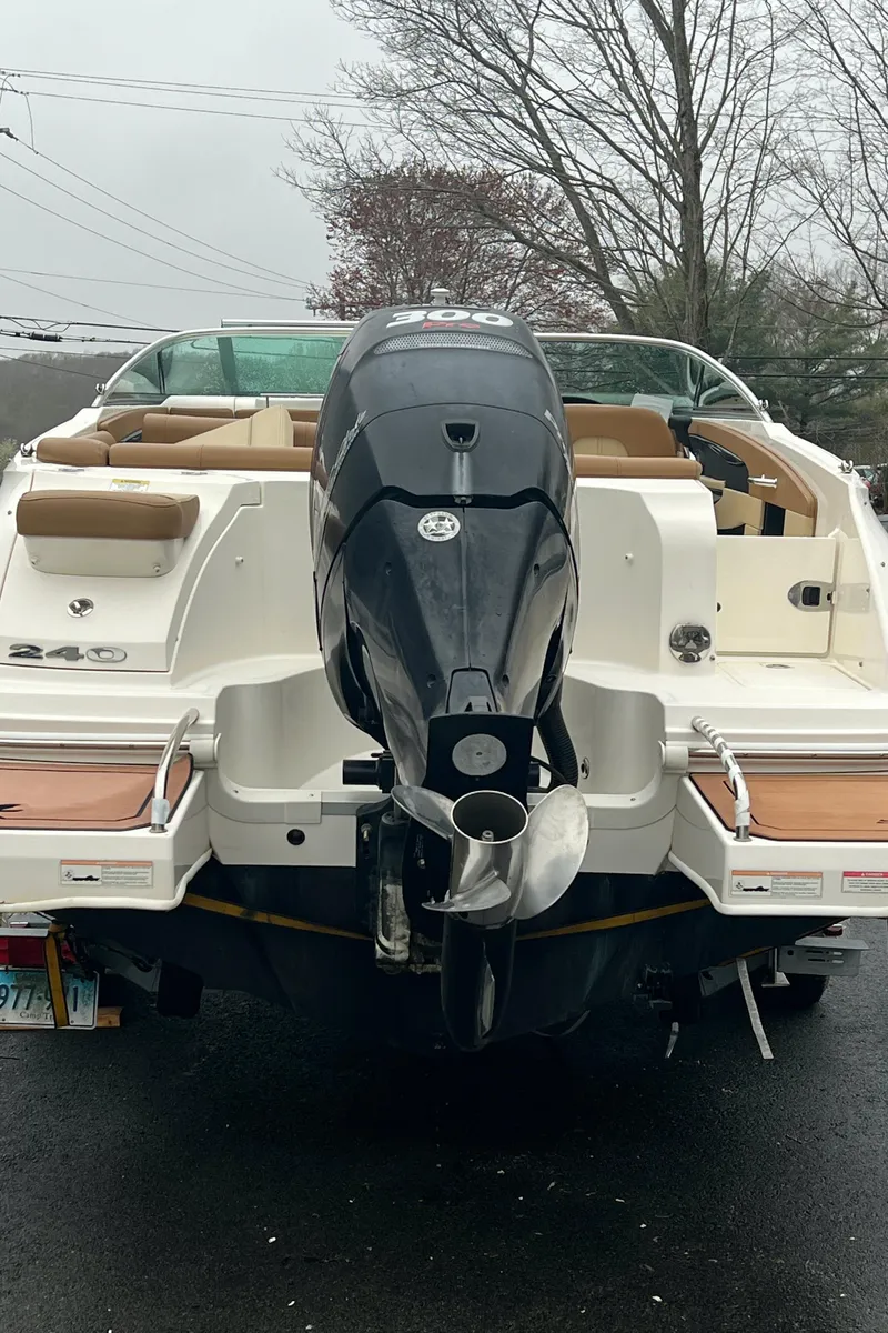Slide: The Image of 2014 Sea Ray 240 Sundeck Outboard boat, rear view with motor, parked on a driveway. - 6