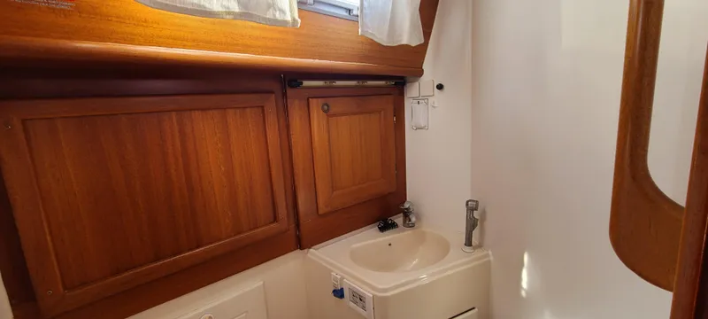 Slide: The Image of Compact bathroom in a 1999 Malo 45 yacht with wooden cabinets and a small sink. - 21