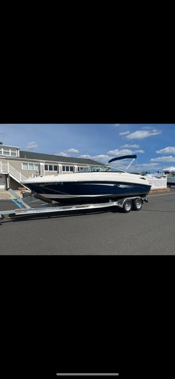 The Image of 2014 Sea Ray 240 Sundeck boat on a trailer in front of a house. - 0