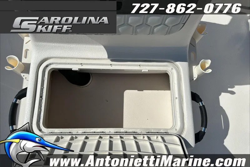 Slide: The Image of 2024 Carolina Skiff E21 DLX CC boat storage compartment with rod holders, contact info, and logo. - 21