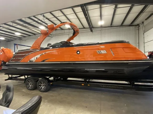 Slide: The Image of 2024 Bennington 27 QXFBWA T2 pontoon boat in orange and black, displayed indoors. - 4