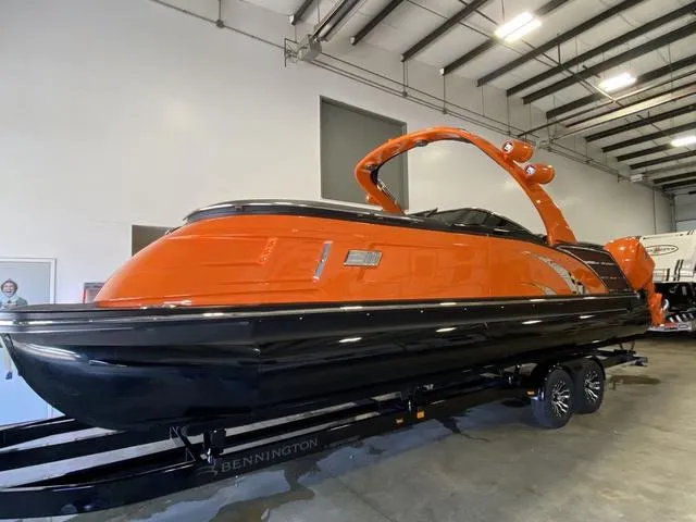 Slide: The Image of 2024 Bennington 27 QXFBWA T2 pontoon boat in orange and black on trailer. - 5