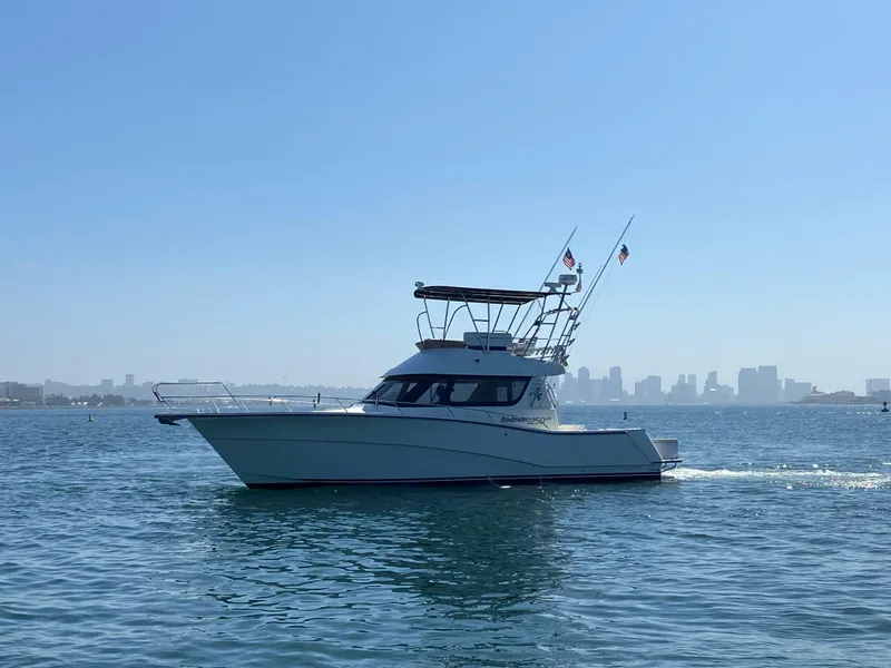 Slide: The Image of 2014 Rodman 1250 ADV Fisher Cruiser on calm water with city skyline in background. - 0
