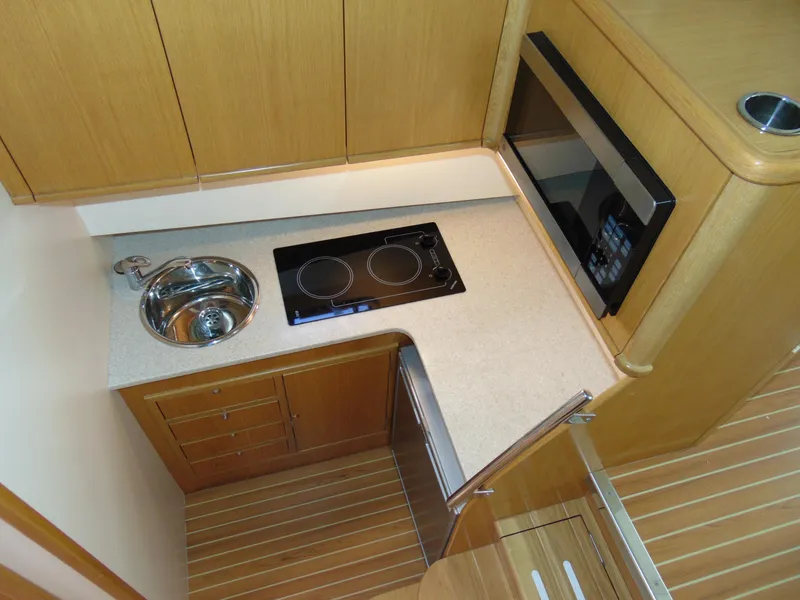 Slide: The Image of Compact kitchen area in a 2014 Rodman 1250 ADV Fisher Cruiser with stove, sink, and microwave. - 11