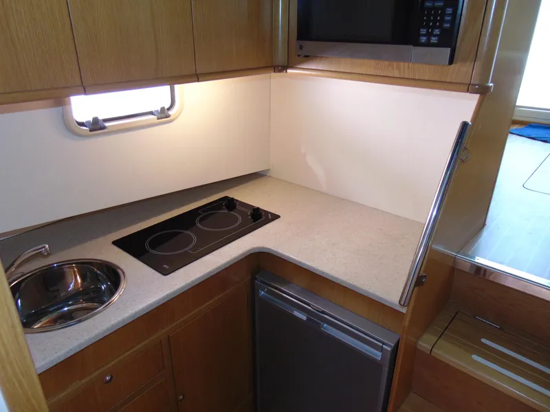 Slide: The Image of Compact kitchen area in 2014 Rodman 1250 ADV Fisher Cruiser with stove, sink, and mini-fridge. - 12