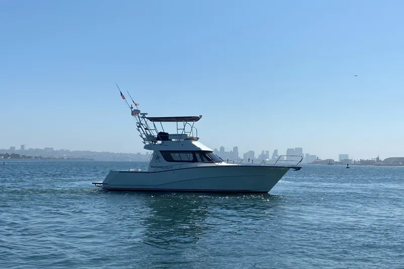 Slide: The Image of 2014 Rodman 1250 ADV Fisher Cruiser on calm waters with city skyline in background. - 27