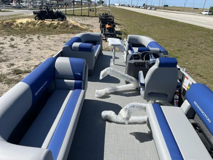 Slide: The Image of 2024 Bennington S 20 SSR pontoon boat with blue and gray seating, parked near a highway. - 17