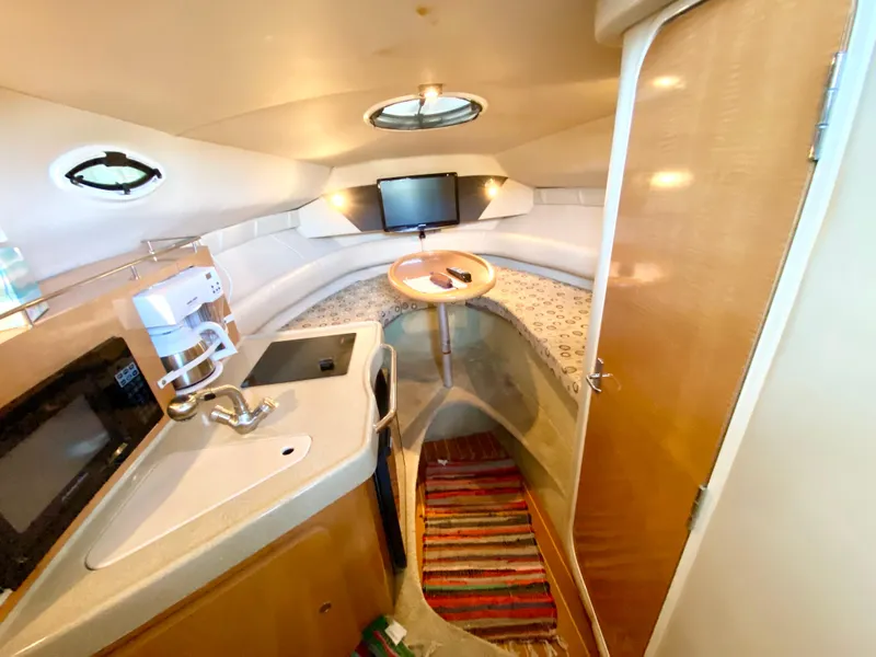 Slide: The Image of 2008 Larson Cabrio 240 cabin interior with kitchenette, seating area, and TV. - 15