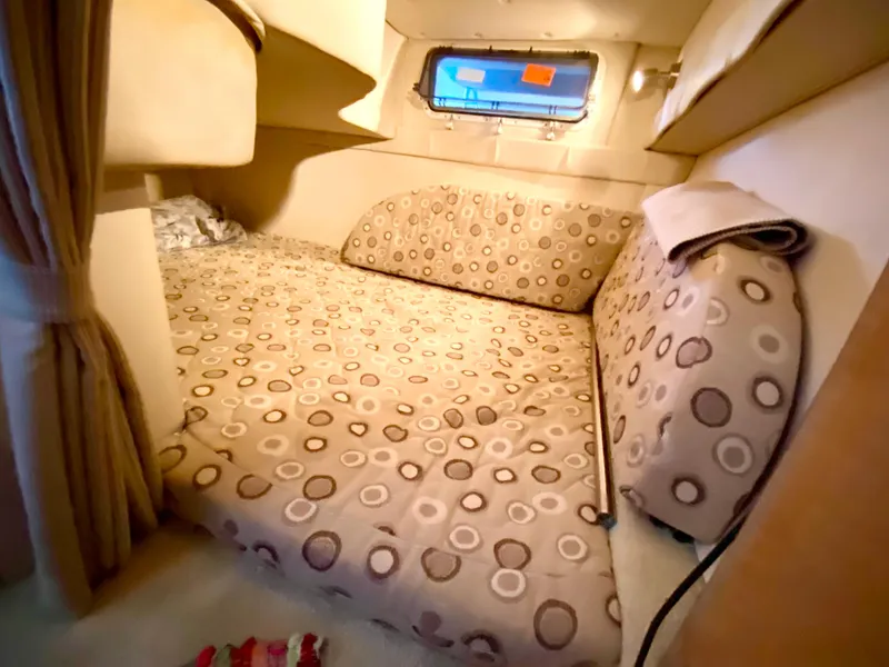 Slide: The Image of 2008 Larson Cabrio 240 cabin interior with cozy bed and porthole window. - 17