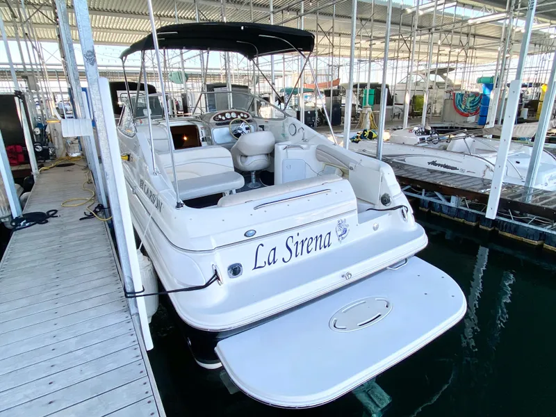 Slide: The Image of 2008 Larson Cabrio 240 boat docked, named La Sirena, with a spacious deck and canopy. - 2