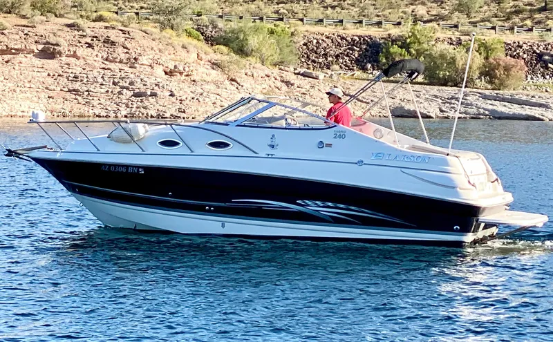 Slide: The Image of 2008 Larson Cabrio 240 boat cruising on a lake with a person at the helm. - 4