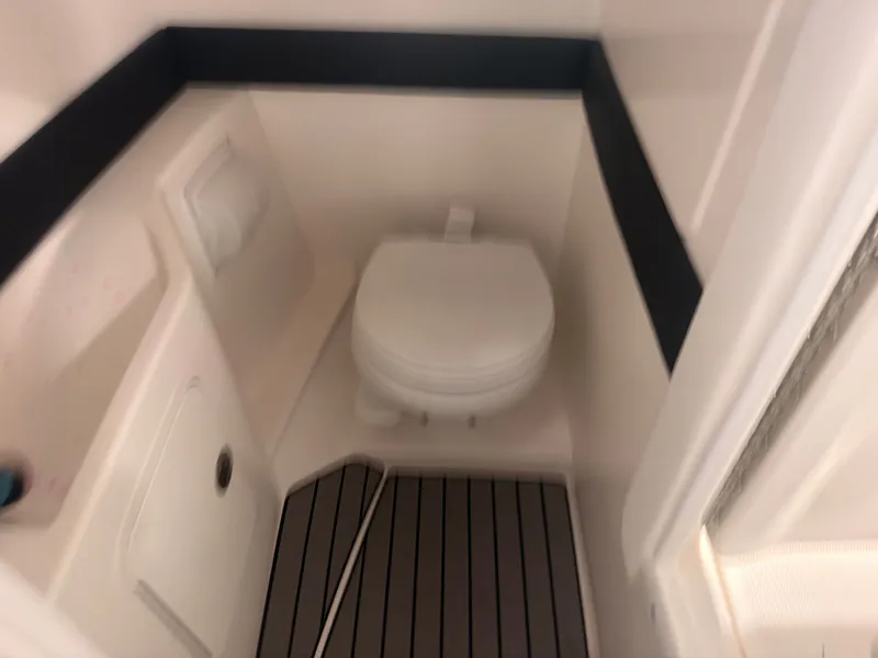 Slide: The Image of The image shows a compact boat toilet with white walls and a black stripe. - 30