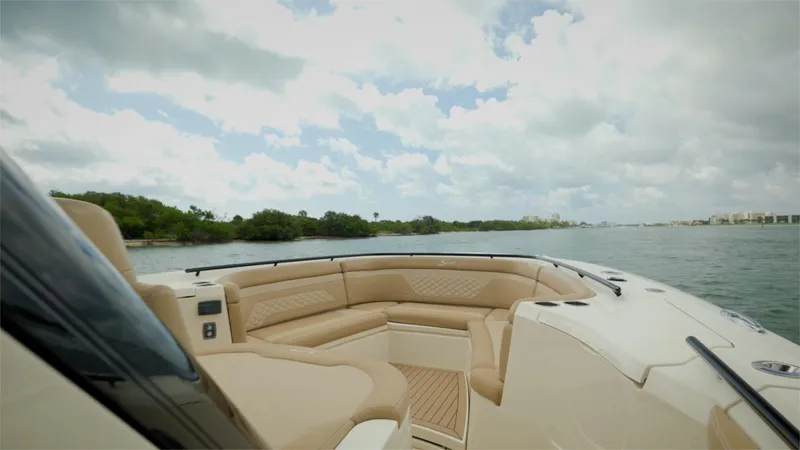 Slide: The Image of 2022 Scout 330 LXF boat interior with beige seating on a sunny day. - 13